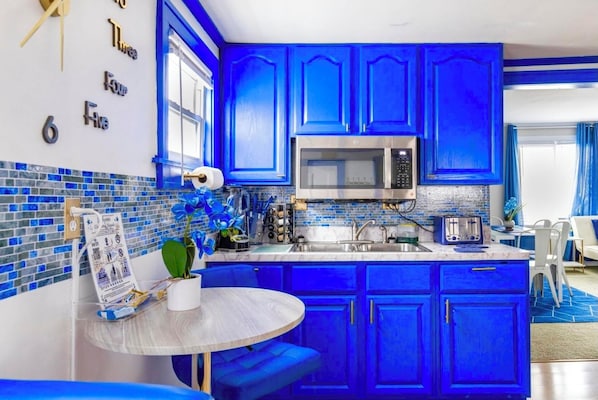 Kitchen features a microwave, toaster, and potted plant, with a blue backsplash and ample counter space.