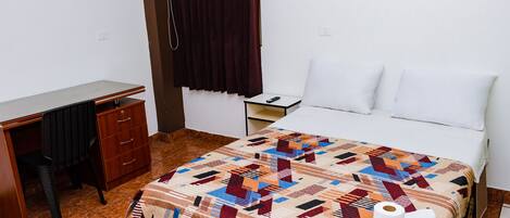 A hotel room with a bed, a desk, and a chair.