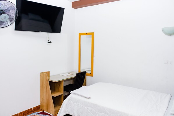 A hotel room with a bed, a desk with a chair, a television, and a mirror. - Hotel Zentrico (Chiclayo)