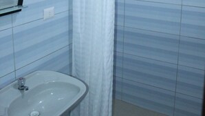 A bathroom with a white sink, a shower curtain, and tiled walls. - Hotel Zentrico (Chiclayo)