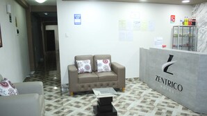 Un área de recepción con un sofá, una mesa de vidrio y un suelo con diseño de mármol.