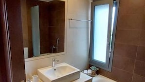 Une salle de bain moderne avec un grand lavabo, un miroir, une baignoire et une fenêtre.
