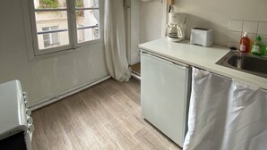 Une petite cuisine avec une fenêtre, un ventilateur de plafond et un évier.