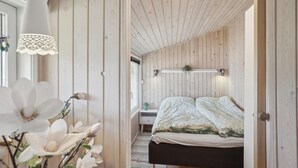 Ein Schlafzimmer mit Holzboden, einem Bett mit Blumenmusterdecke, einem Nachttisch, einer Wandleuchte und einer Pendelleuchte.