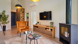 A modern living room with a sofa, a coffee table, a TV, a fireplace, and a bookshelf. - WELLNESS HOUSE BY THE LAKE (Brezova Gora)