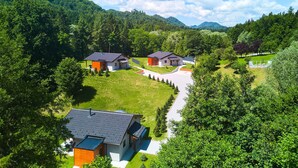 A modern residential area with multiple houses, surrounded by lush greenery and hills. - WELLNESS HOUSE BY THE LAKE (Brezova Gora)