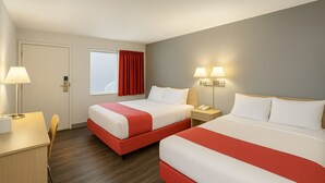 Une chambre d’hôtel avec deux lits, un bureau et une chaise.