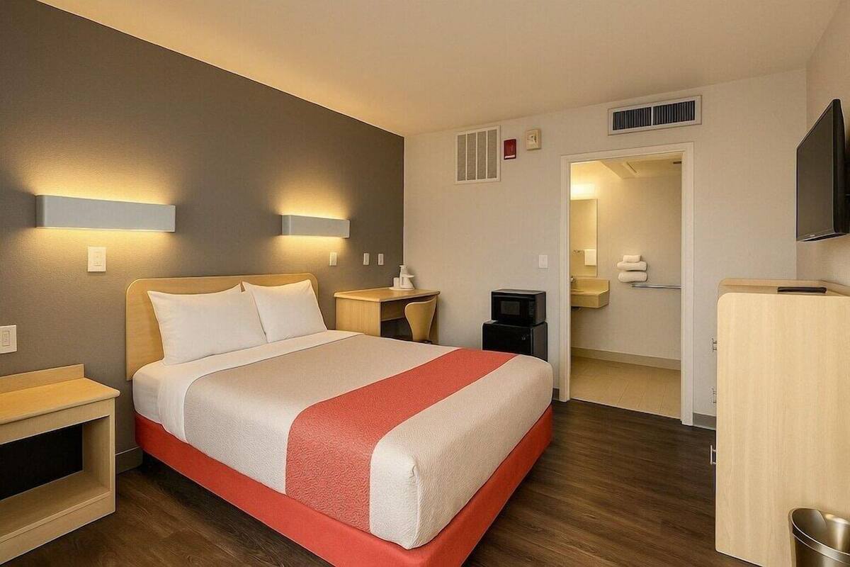 A hotel room with a bed, bedside tables, a TV, a desk, and a wardrobe.