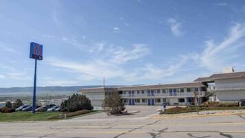 A motel with a large sign, a parking lot, and a building with multiple windows.