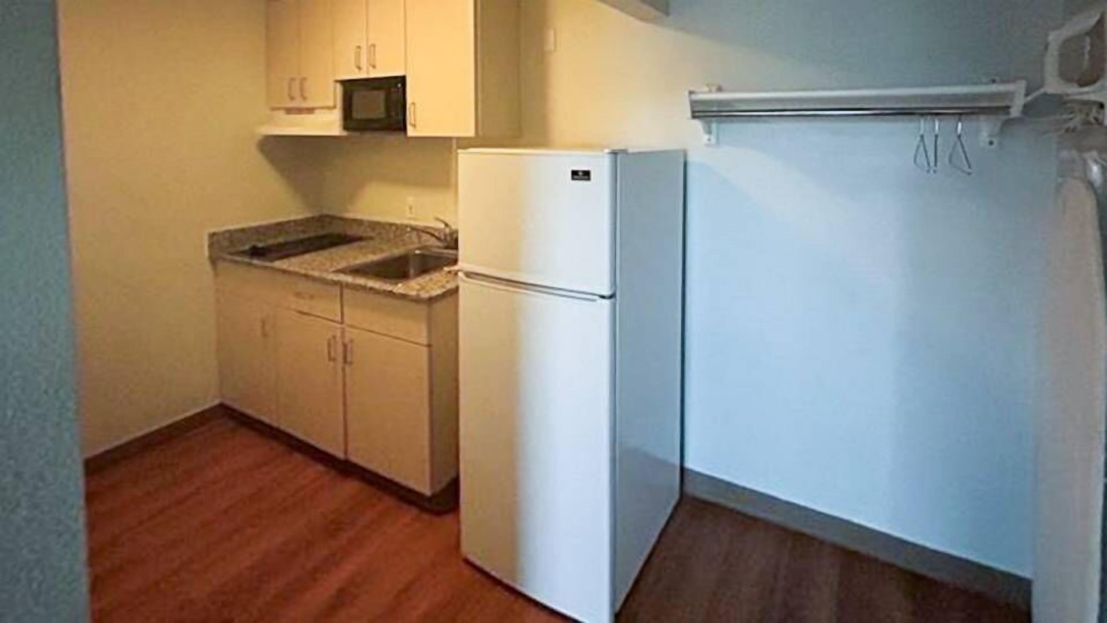 Una cocina pequeña con refrigerador, microondas y armarios de madera.