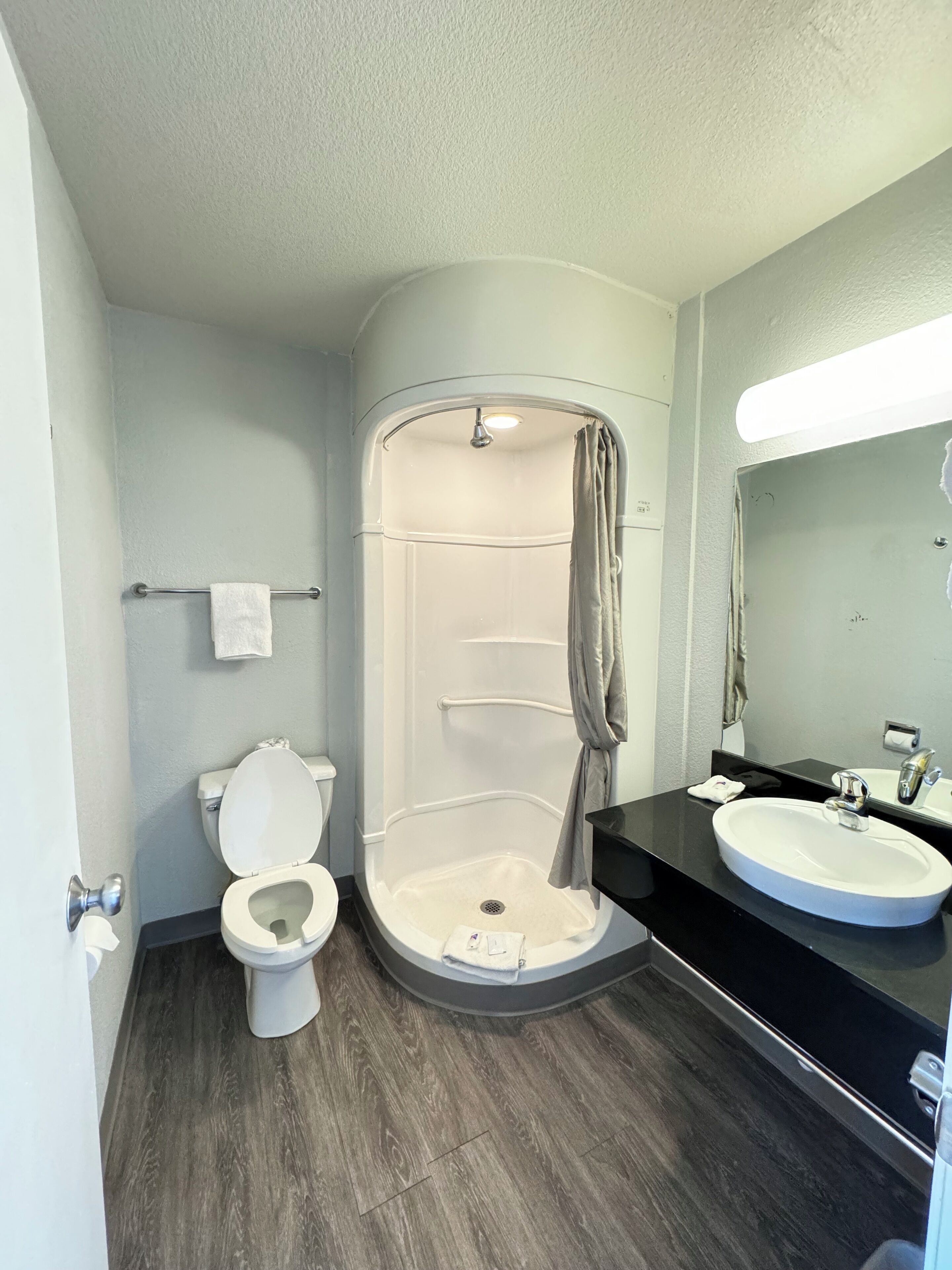 A modern bathroom with a toilet, a shower, and a sink.
