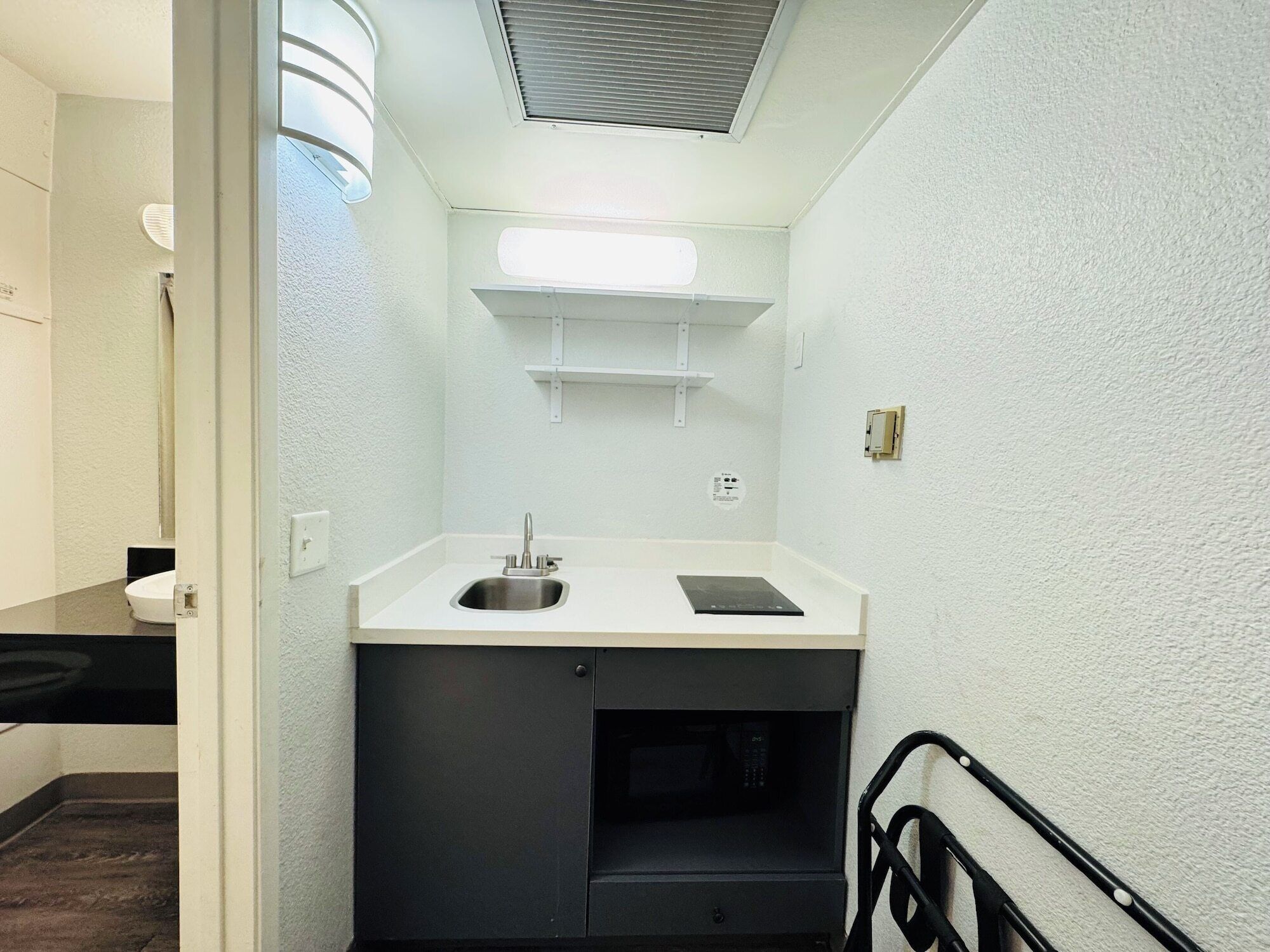 Una kitchenette compacta con un lavamanos, un microondas y una pequeña encimera.