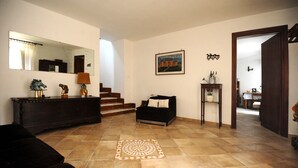 A living room with a sofa, a coffee table, a fireplace, and a staircase leading to another room. - ANCIENT FARMHOUSE SURROUNDED BY GREENERY (Sezze)