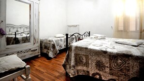 A room with two beds, a large mirror, and a wooden floor. - ANCIENT FARMHOUSE SURROUNDED BY GREENERY (Sezze)