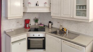 A compact kitchen with white cabinetry, a built-in oven, a dishwasher, a coffee maker, and a sink. - Cozy apartment in Rtina with WiFi (Rtina)