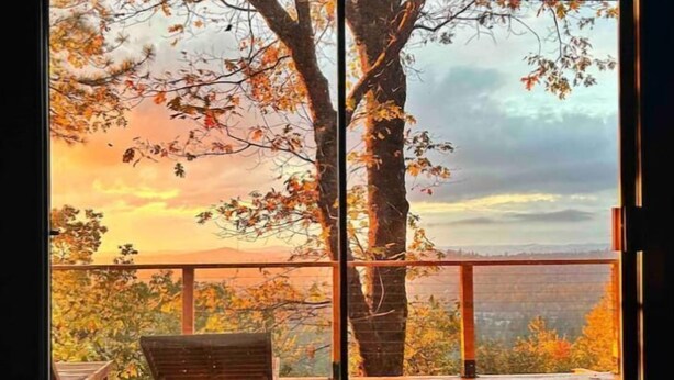 Una habitación con un amplio ventanal corredero que da a una terraza exterior con un banco de madera.