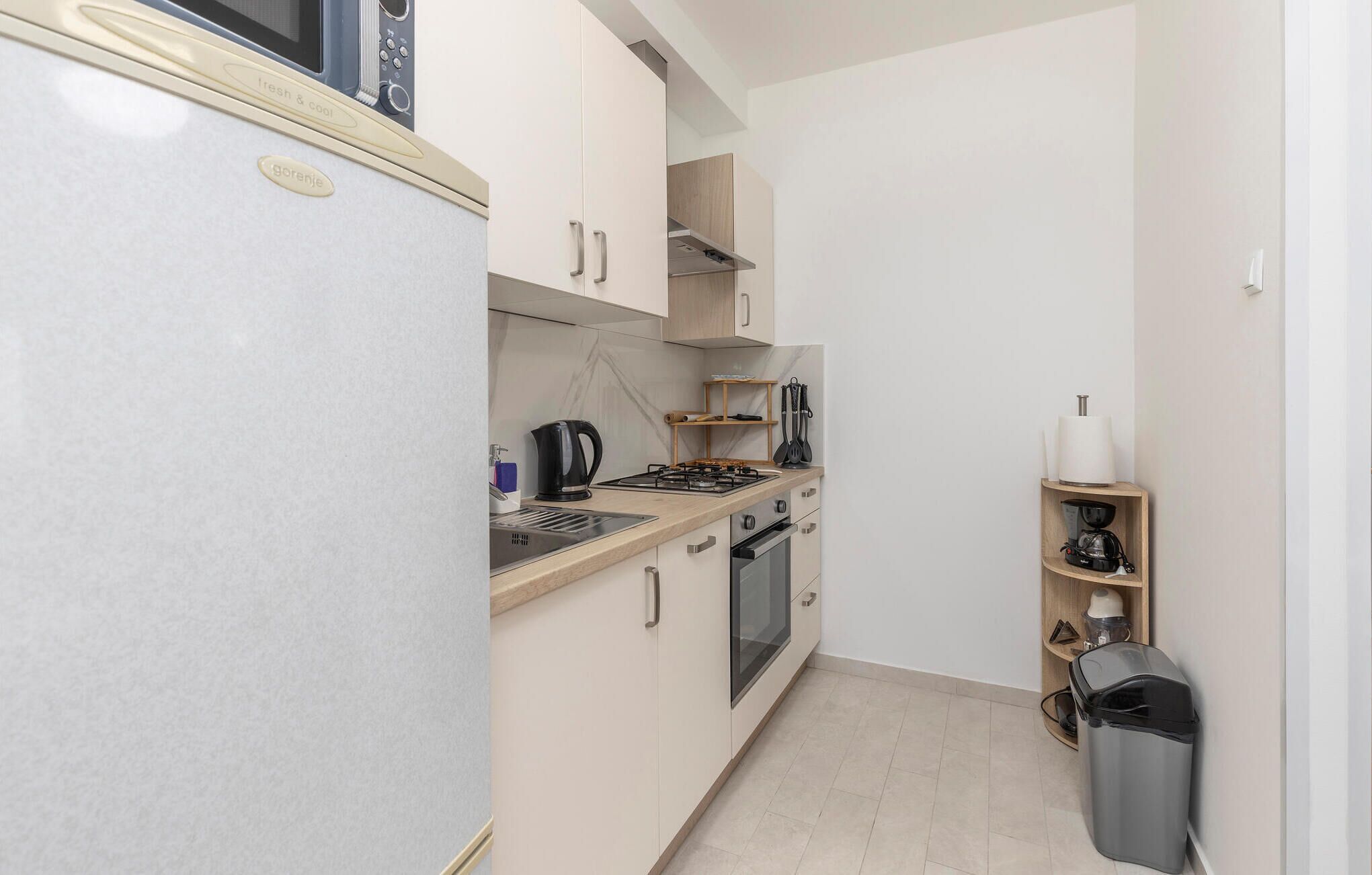 A compact kitchen with a refrigerator, stove, oven, and a coffee machine.