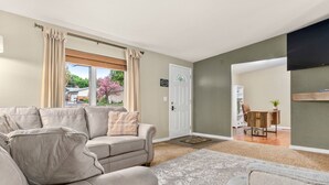 A living room with a beige sofa, a patterned rug, and a door leading to a dining area. - A Getaway Home~ Families & Big Groups  (Lewiston)
