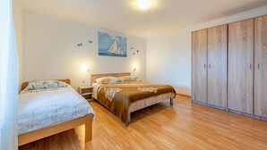 A bedroom with two beds, a wooden wardrobe, and a painting of sailboats on the wall. - Beautiful apartment in Kustici with WiFi (Kustici)