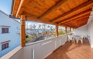 Ein überdachter Balkon mit Blick auf das Meer, weiße Stühle und ein Fliesenboden.