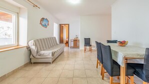 A spacious living area with a sofa, dining table, and chairs. A small table with a plant is visible in the background. - Beautiful apartment in Kustici with WiFi (Kustici)