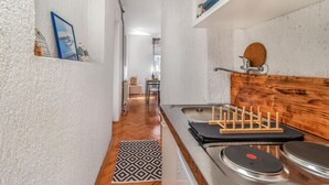 Ett smalt kök med en träbänkskiva, en diskho och en liten matplats i bakgrunden.