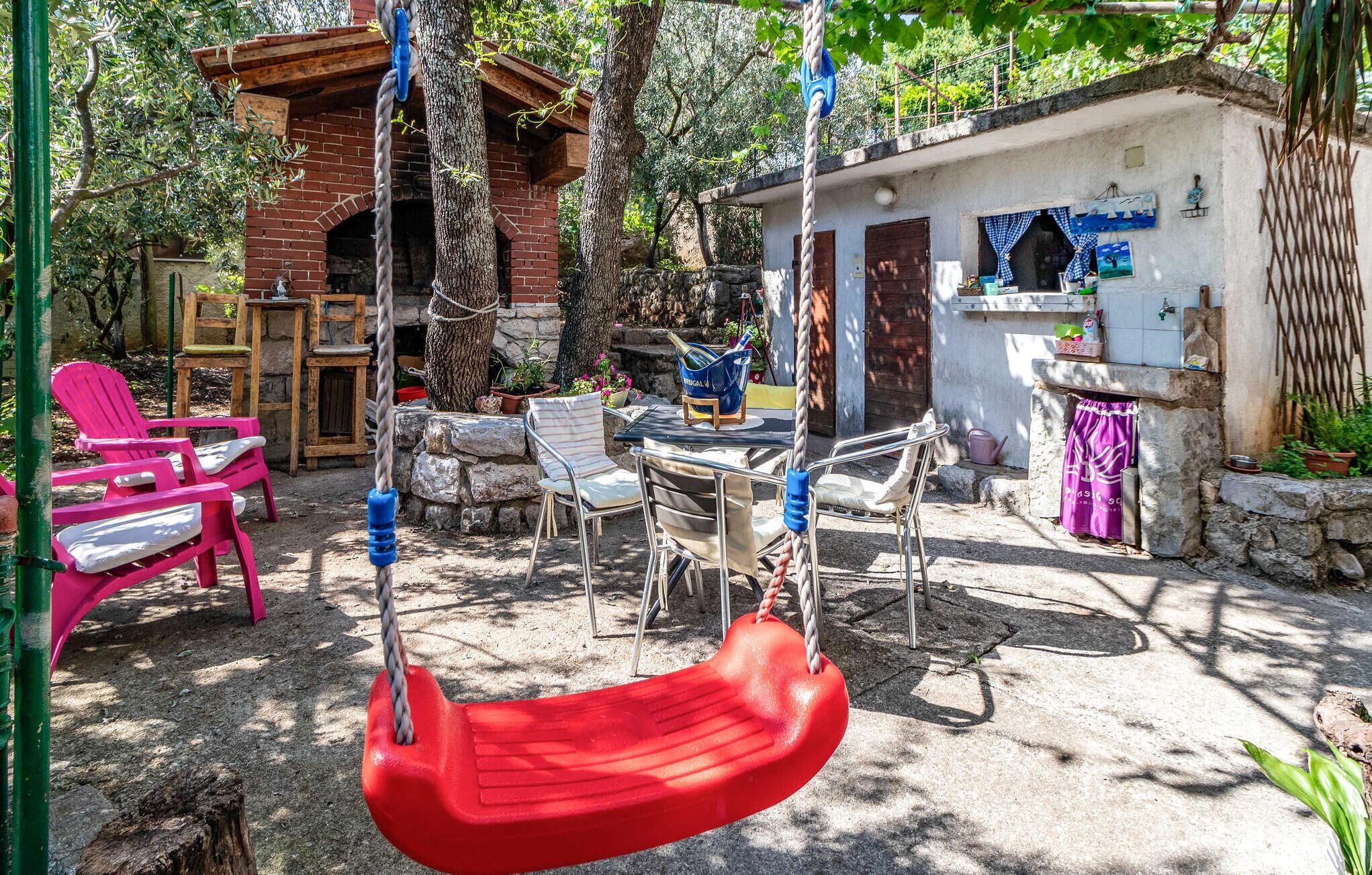 A rustic outdoor seating area with a swing, chairs, and a small table.