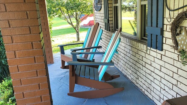 A porch with two rocking chairs, a brick wall, and a window with a wreath.