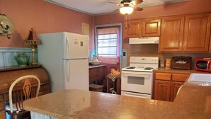 A kitchen with a refrigerator, stove, microwave, and wooden cabinets.