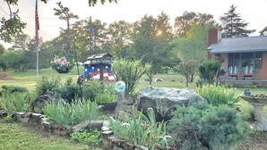A garden with a rock feature, a bird bath, and a flag-painted structure.