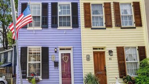 A row of colorful houses with distinct architectural styles, including a purple house with a flag and a yellow house with a number '81' sign. - Historic Home with Parking Steps From Capital & USNA (Annapolis)