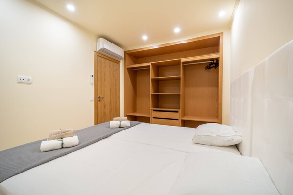 Una habitación de hotel con una cama, un armario de madera y una mesita con toallas.