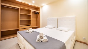 Een slaapkamer met een bed, een houten garderobe en een kapstok.