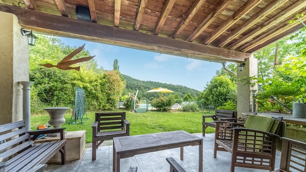 Eine überdachte Terrasse mit Holzmöbeln, einem Tisch und Stühlen.
