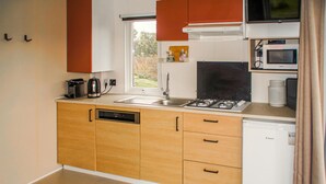 Una cocina compacta con armarios de madera, un lavamanos, una estufa y un microondas.