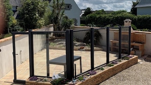 A patio with a glass enclosure, brick planters, and a view of neighboring houses.