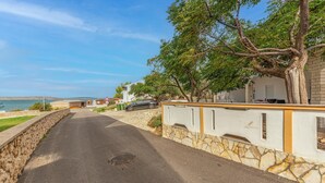Una carretera costera con un muro de piedra y un edificio con balcón.
