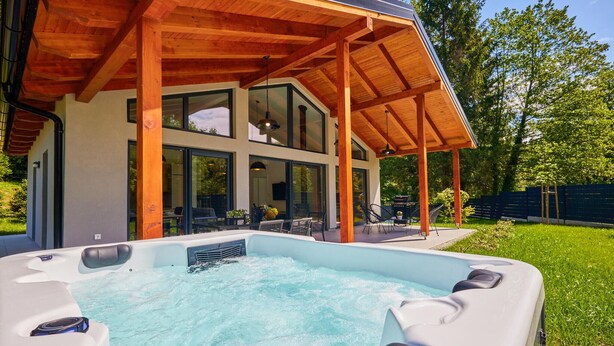 A modern house with a wooden deck, a hot tub, and a patio area. - COZY HOME & SPA IN NATURE (Brezova Gora)