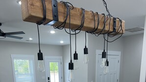 A modern kitchen with a wooden island, black chairs, and pendant lights.