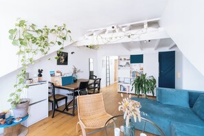 A modern loft apartment with a dining area, a living room, and a bookshelf.