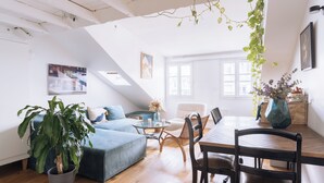 A modern living space with a dining area, a sofa, a coffee table, and a potted plant.