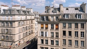 A row of multi-story buildings with balconies, large windows, and a clear sky.