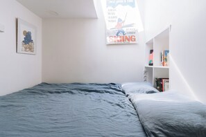 A bedroom with a bed, a poster on the wall, and a bookshelf. - Beautiful, Sun-kissed Studio—Faubourg Saint-Martin (Paris)
