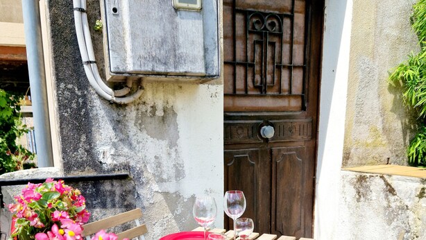 An outdoor dining area with a table set for two, a wooden door, and potted plants. - Maisonnette du Foirail, Proche Centre-ville Espalion. À 1 min des Berges du Lot! (Espalion)