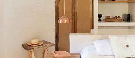 Un dormitorio con una cama, muebles de madera, una lámpara colgante y una pared blanca.
