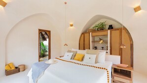 A bedroom with a large bed, wooden headboard, and a bedside table with a bowl. - Villa Sanah (Tulum)