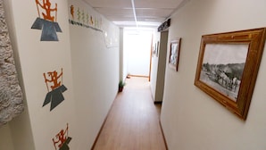 A hallway with artwork on the walls, a wooden floor, and a framed picture on the right. - CENTRAL PLAZA APARTMENTS (Cusco)
