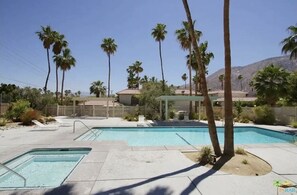 Ein Poolbereich mit mehreren Pools, Palmen und einem Berg im Hintergrund.