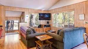 A cozy living room with a sofa, a coffee table, and a TV mounted on the wall. - Yosemite's Riverfront Retreat (Yosemite National Park)