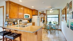 A kitchen with wooden cabinets, a microwave, a refrigerator, and a dining area with chairs and a table. - Emory Vacation Rental w/ Lake Fork Boat Access! (Emory)